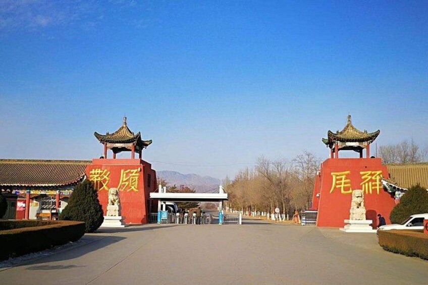 A traditional gate with Chinese characters, a clear sky, and a distant mountain range. 3