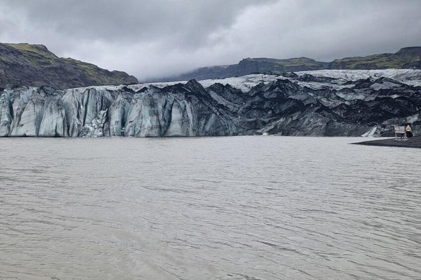 A glacier with a small boat on the water. 2