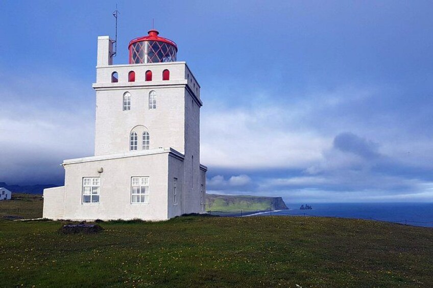 A lighthouse with a red top, white walls, and a grassy foreground. 4