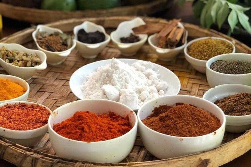 A variety of spices and herbs in small bowls on a woven tray. 3