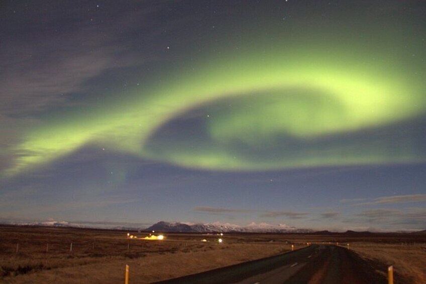 A road with a green aurora display in the sky. 1