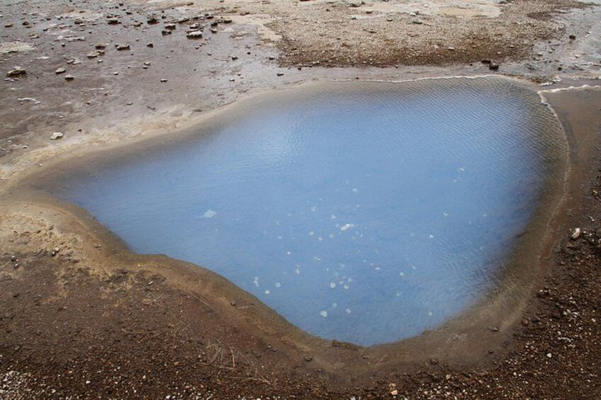 Ein großer, unregelmäßig geformter Teich, umgeben von trockenen, rissigen Boden. 3