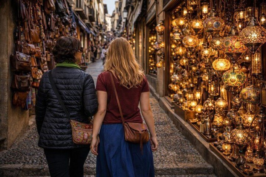 A narrow street with shops on either side, one displaying hanging bags and the other with ornate lanterns. 5