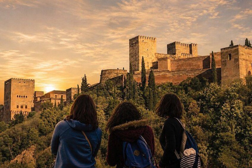 Tres personas de pie observando un castillo histórico con torres y muros. 5