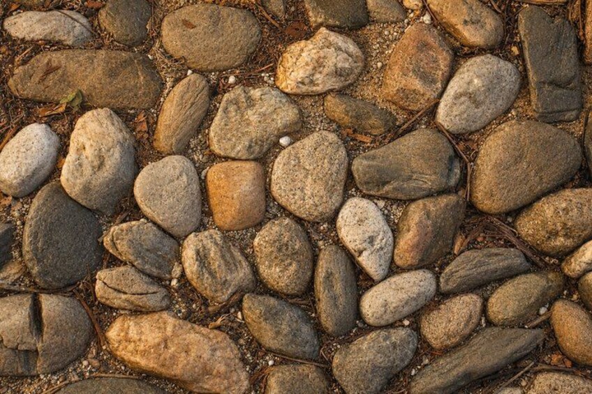 A close-up of a ground surface covered with variously sized and shaped stones. 2