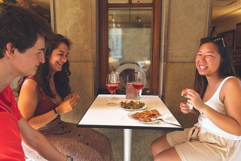 Three people sitting at a table with food and drinks. 4