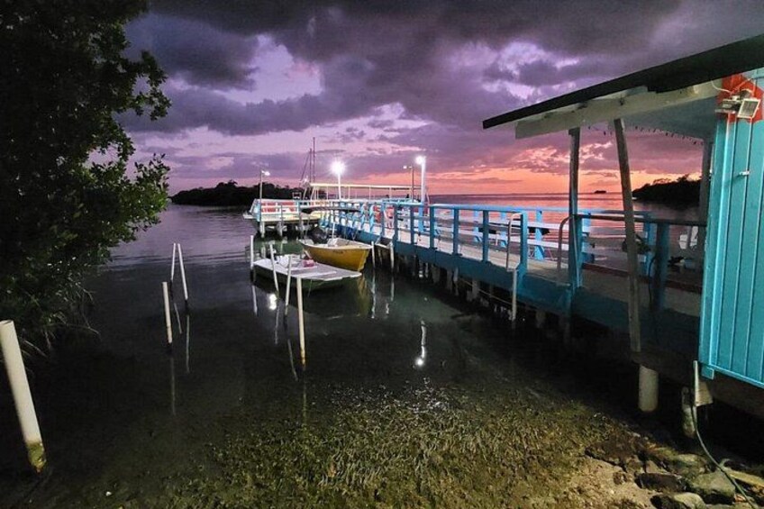 A dock with boats, a pier, and a sunset over water. 3