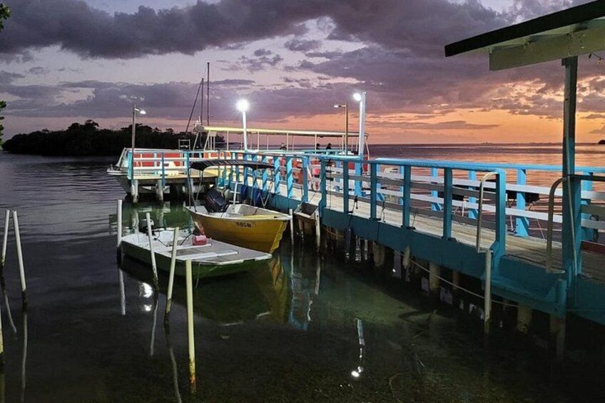 A dock with boats, a pier, and a sunset over water. 2