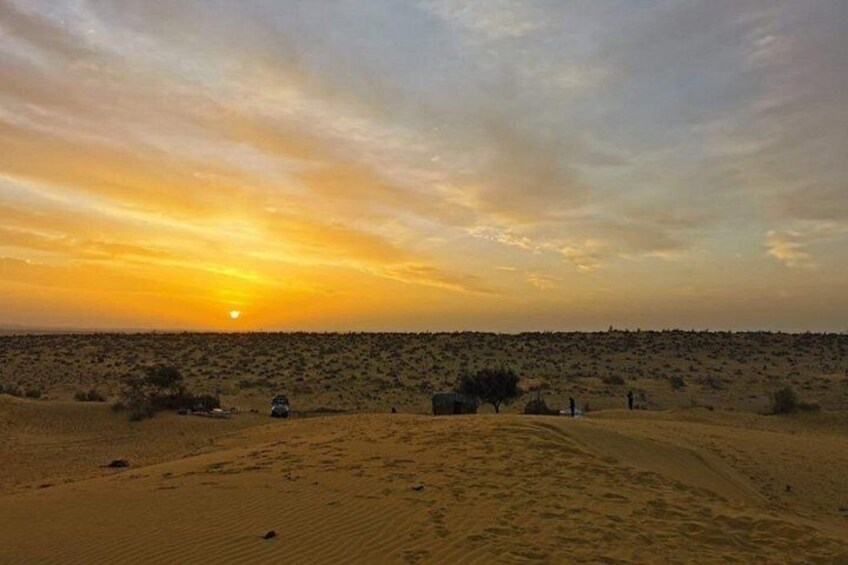 Paisaje desértico al atardecer con dunas de arena y vegetación escasa. 2