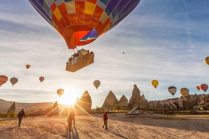 A hot air balloon festival with multiple balloons, a desert landscape, and pyramidal rock formations. 2