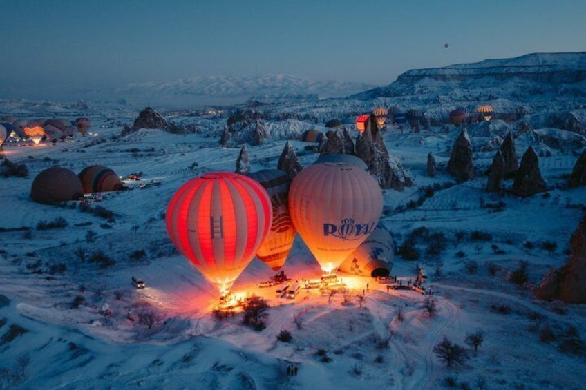 Palloncini aerostatici sopra un paesaggio innevato con formazioni rocciose particolari. 2