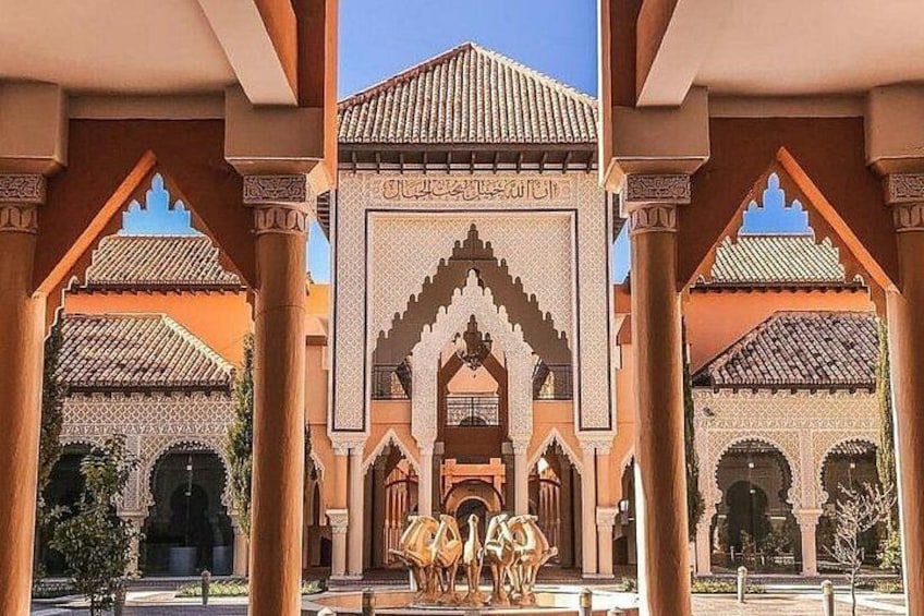 Ein Innenhof mit Bögen, einer zentralen Fontäne und einem Gebäude mit aufwendigen Verzierungen. 1