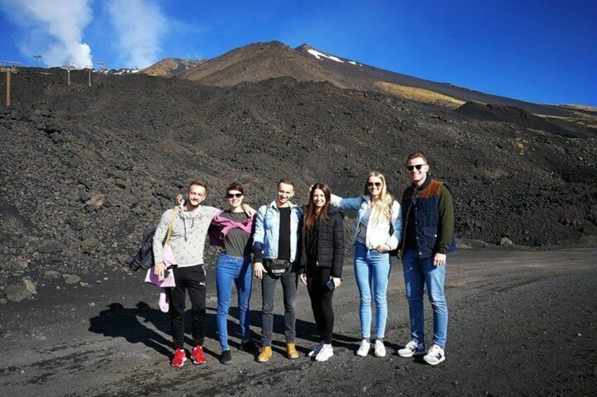 A group of people standing on a road with a volcanic landscape in the background. 2