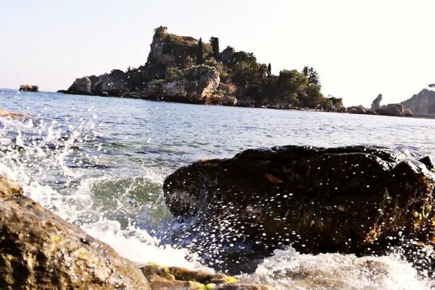A rocky shoreline with waves crashing against the rocks and a distant rocky outcrop. 2