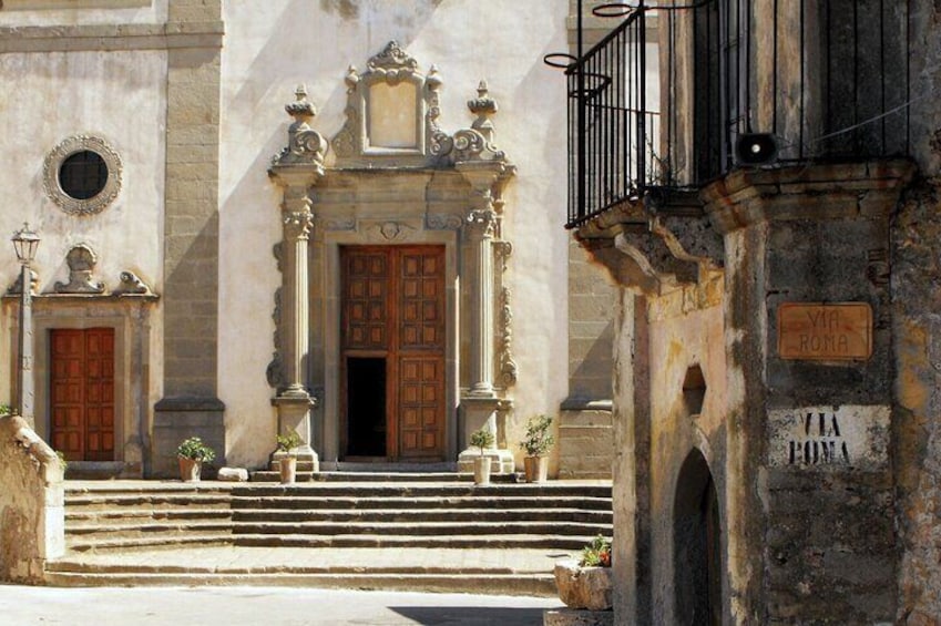 A historic building with ornate doors, a staircase, and a sign reading 'Via Roma'. 4