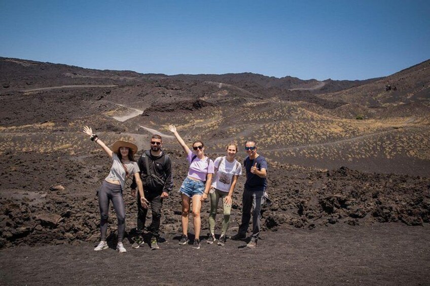 A group of people standing on a volcanic landscape with a clear sky. 3