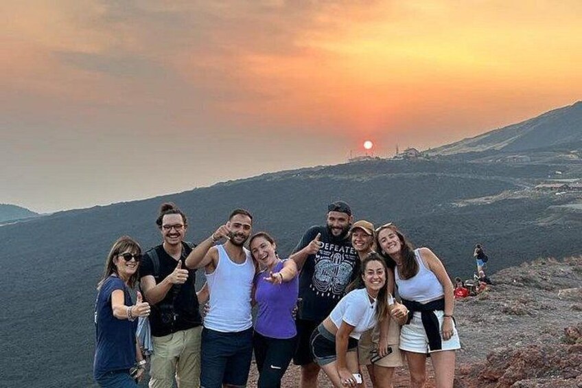 Un groupe de personnes posant sur une montagne, avec un coucher de soleil en arrière-plan. 5