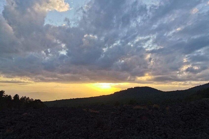 Un coucher de soleil sur un paysage vallonné, avec des nuages. 2