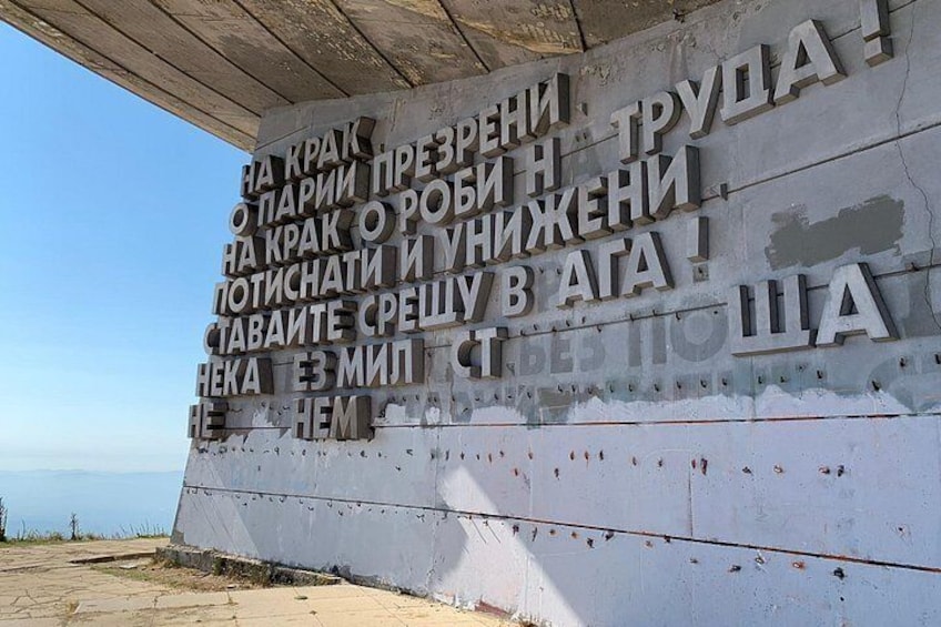 A weathered wall with Cyrillic text, possibly a memorial or historical marker. 2