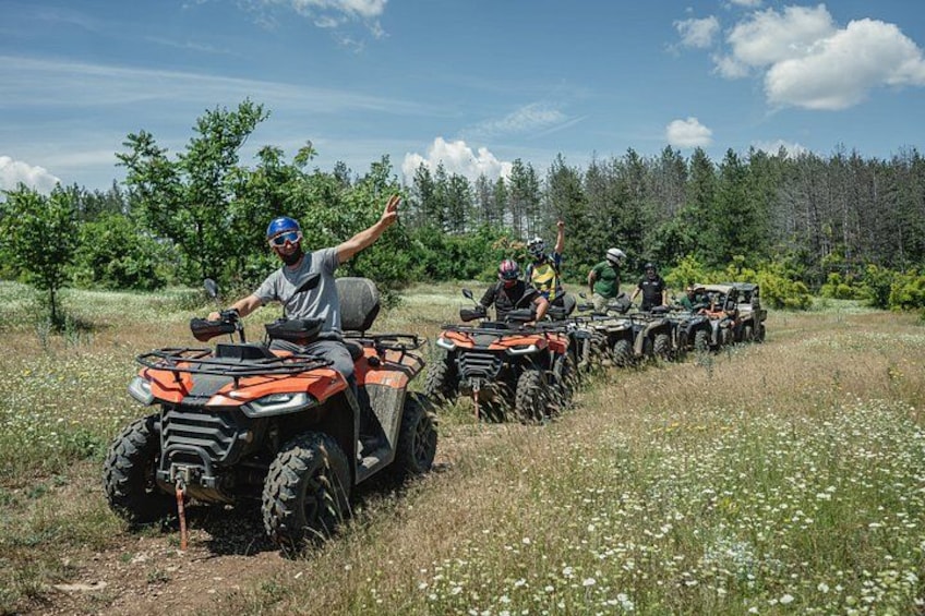 A group of people on ATVs in a grassy field with trees in the background. 1