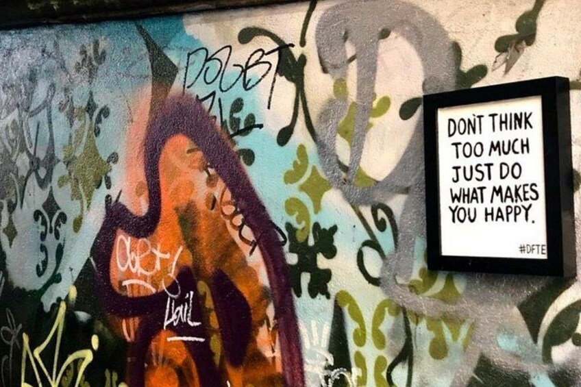 A wall with graffiti and a motivational quote. 2