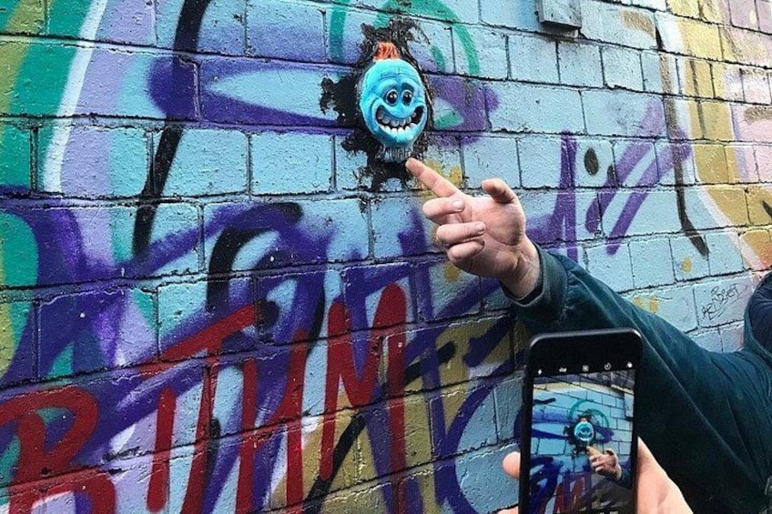 A hand pointing at a graffiti wall with a cartoonish face and the word 'BRINE' visible. 3