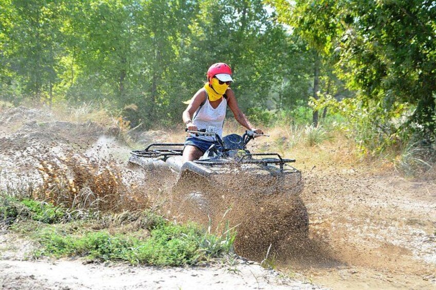 A person riding a quad bike on a dirt trail surrounded by greenery. 5