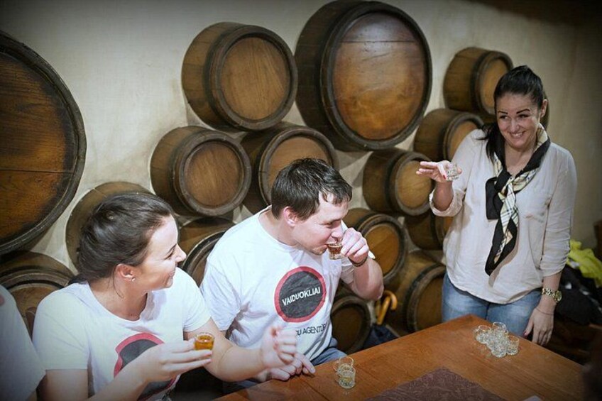 Persone che assaggiano vino in una cantina con botti di legno. 2