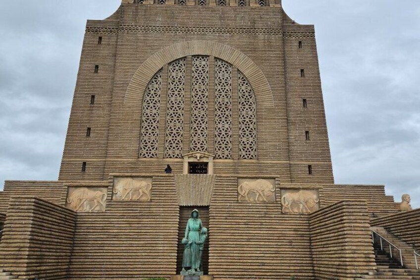 Un edificio de ladrillo grande con una ventana arqueada destacada y una estatua en su fachada. 2