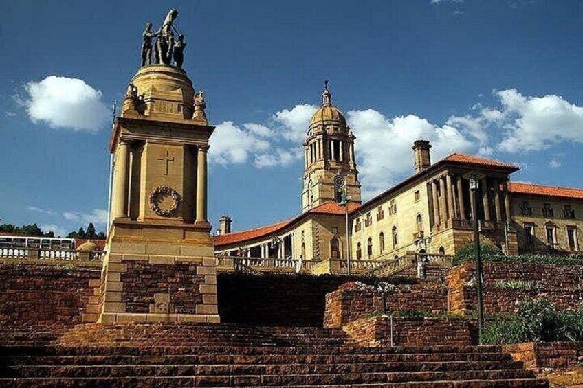 Un edificio histórico con una torre del reloj y una estatua sobre un pedestal. 4