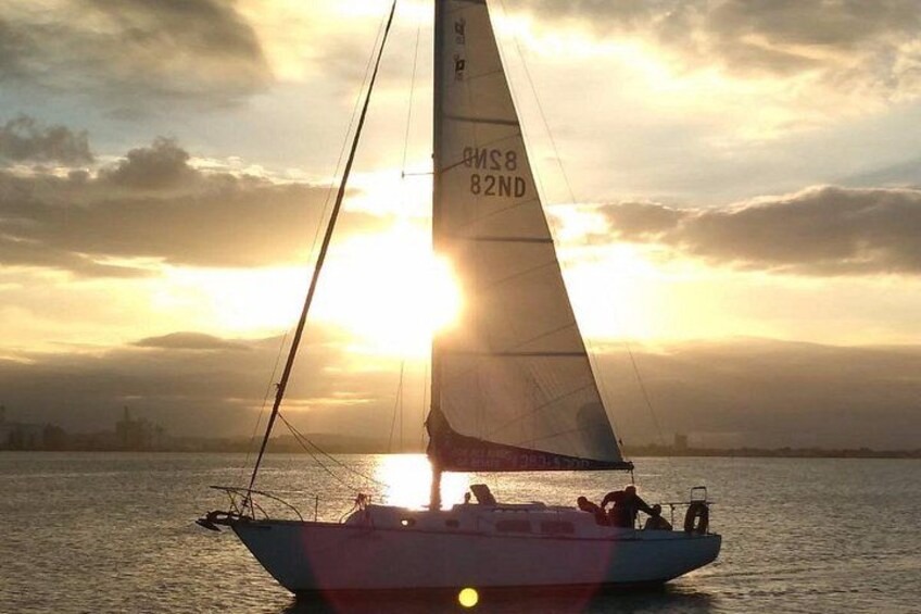 Un voilier portant le numéro d’immatriculation AMS8 82ND navigue sur des eaux calmes au coucher du soleil. 5
