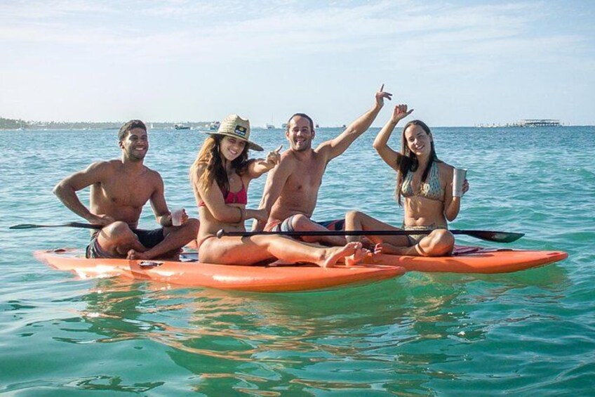Cuatro personas en una tabla de remo naranja en aguas oceánicas tranquilas. 3