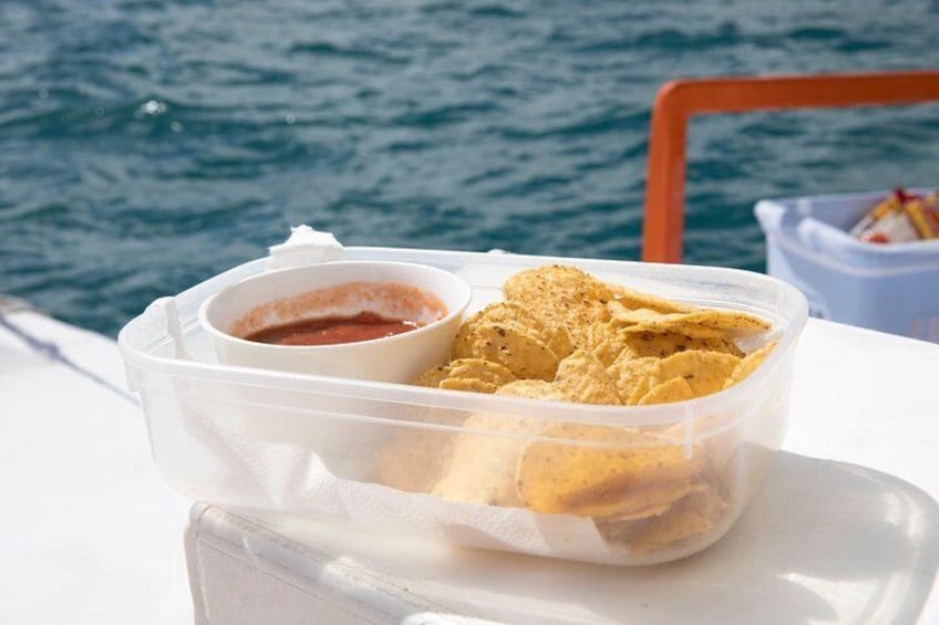 Eine Plastikbox mit Chips und eine kleine Schale Salsa auf einem Boot. 5