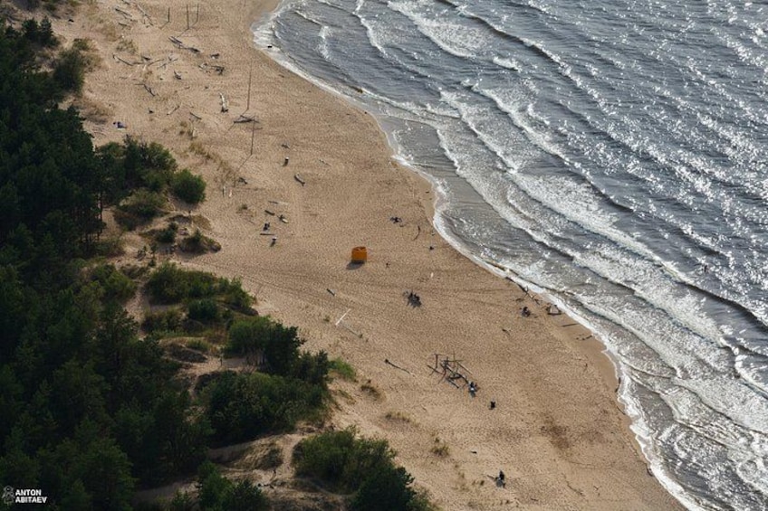 A sandy beach with waves, a yellow object, and sparse vegetation. 5