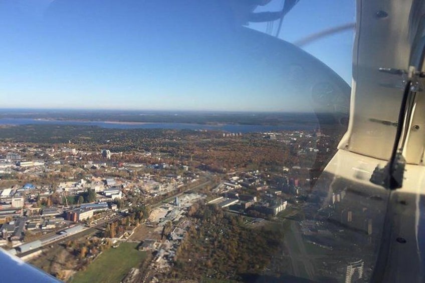 An aerial view of a city with buildings, roads, and a body of water in the distance. 3