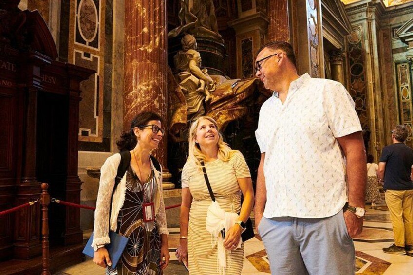 A group of people inside a building with ornate columns and a large golden statue. 4