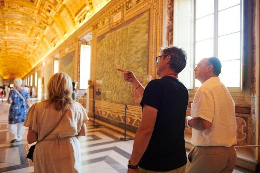 A grand hall with ornate ceiling and walls, a person pointing, and another observing. 2