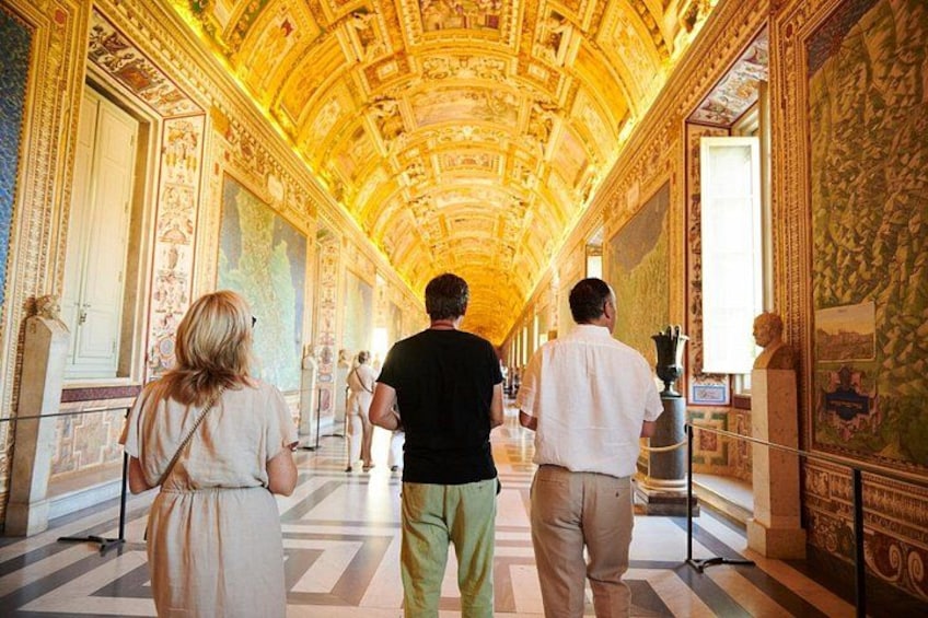 A grand hallway with ornate ceiling and walls, leading to a large open space. 4