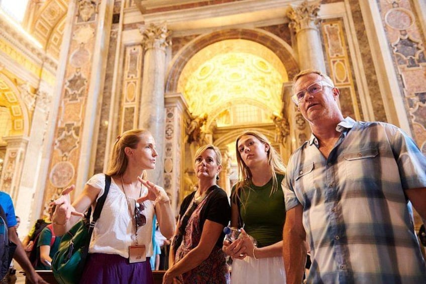 A group of people inside a building with ornate architecture, including columns and a large decorative ceiling. 2