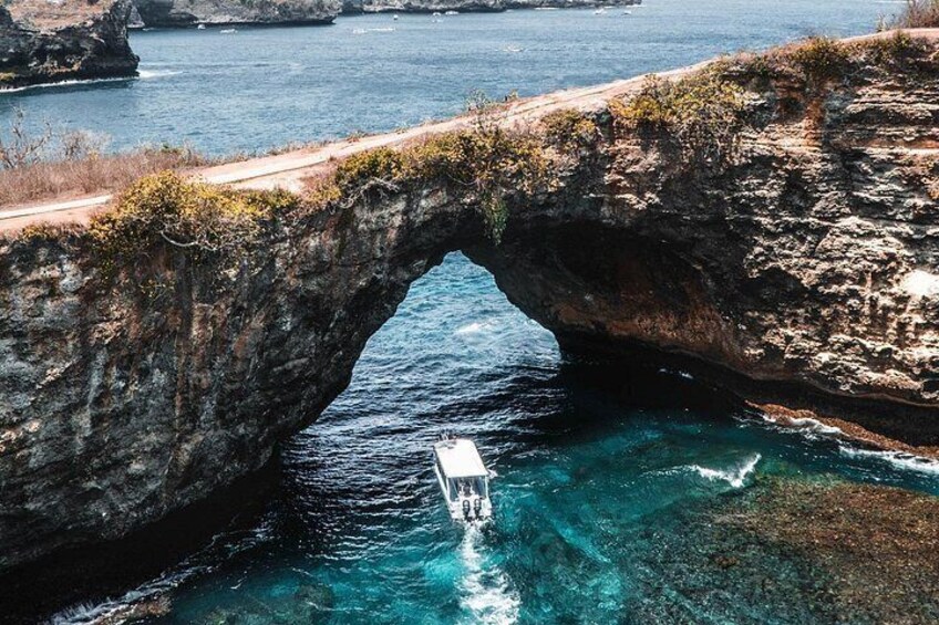 A boat navigating through a natural rock arch formation in a body of water. 5