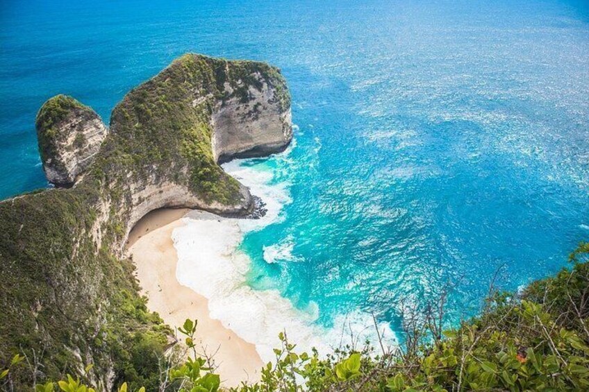 A coastal landscape with a sandy beach, clear blue waters, and rocky formations. 1