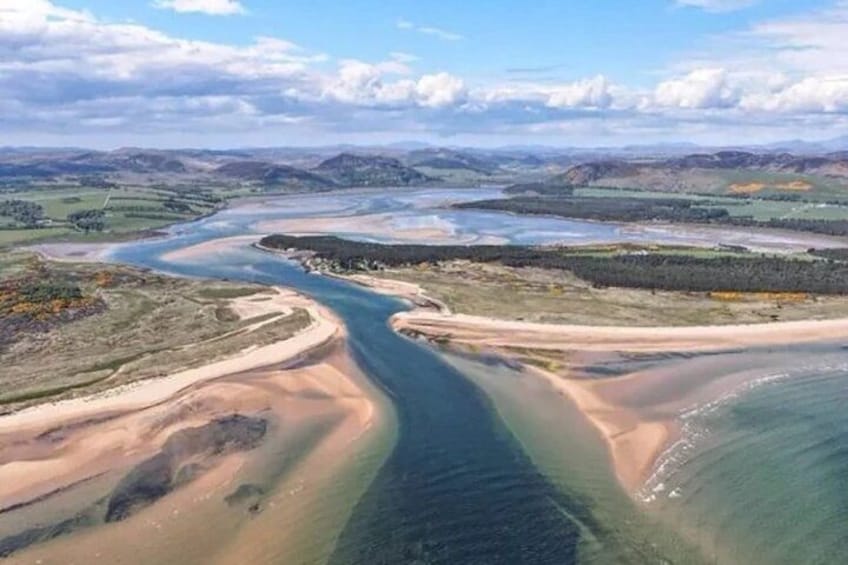 A river meandering through a landscape with sandy banks and distant hills. 2