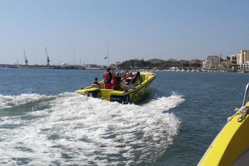 Un velero amarillo con pasajeros en un cuerpo de agua, con estructuras industriales y edificios al fondo. 4