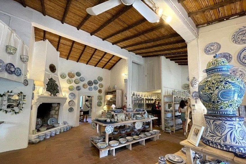 A pottery shop with shelves of bowls and plates, a large decorative vase, and a ceiling fan. 5