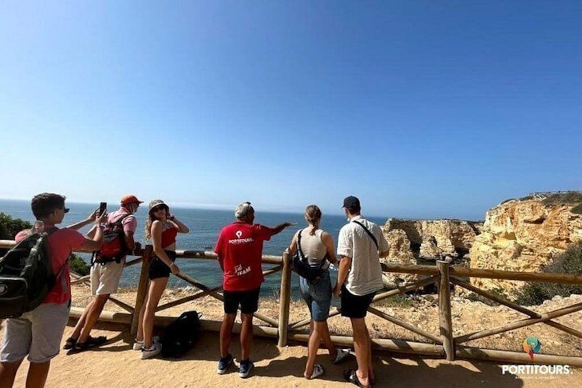 A group of people standing on a wooden platform overlooking a coastal landscape. 4
