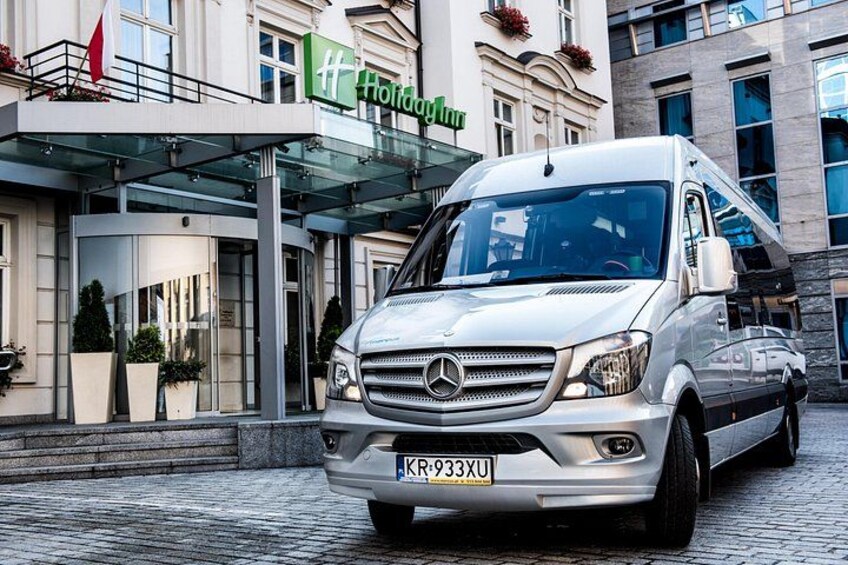 En vit Mercedes-Benz-skåpbil stod parkerad framför ett hotell med en entré av glas. 4