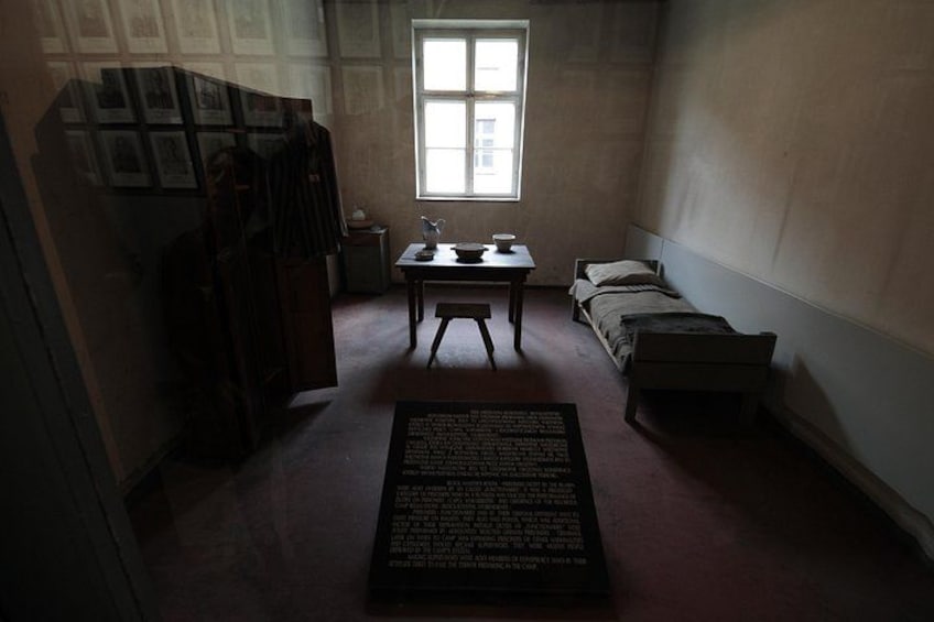 Een kamer met weinig licht, een bureau, een bed en een raam. 2
