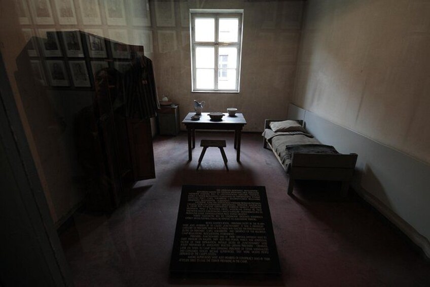 Una habitación tenuemente iluminada con una cama, un escritorio y una ventana. 2