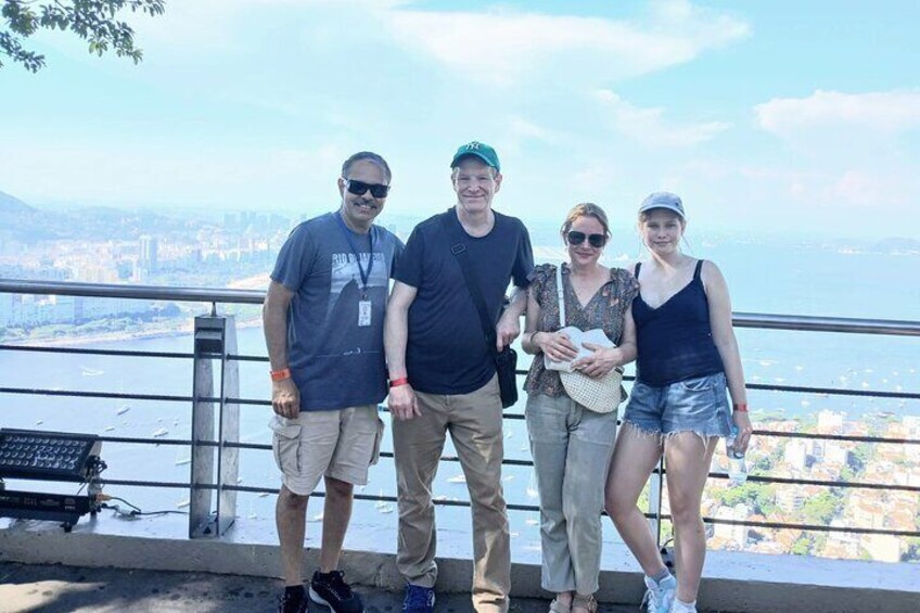 A group of people standing on a balcony overlooking a cityscape with a body of water in the distance. 3