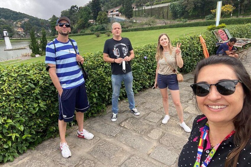 A group of people standing on a stone pathway with a lake and greenery in the background. 1